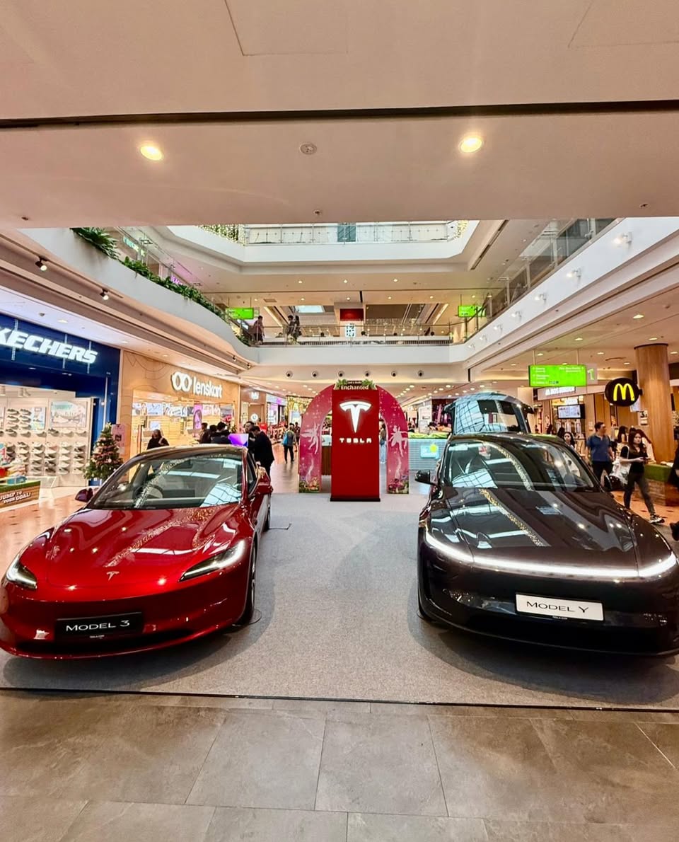 People gathering around Tesla vehicles at a mall event